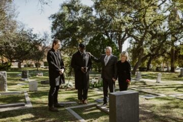 A solemn funeral gathering in a cemetery, capturing an emotional moment of remembrance.